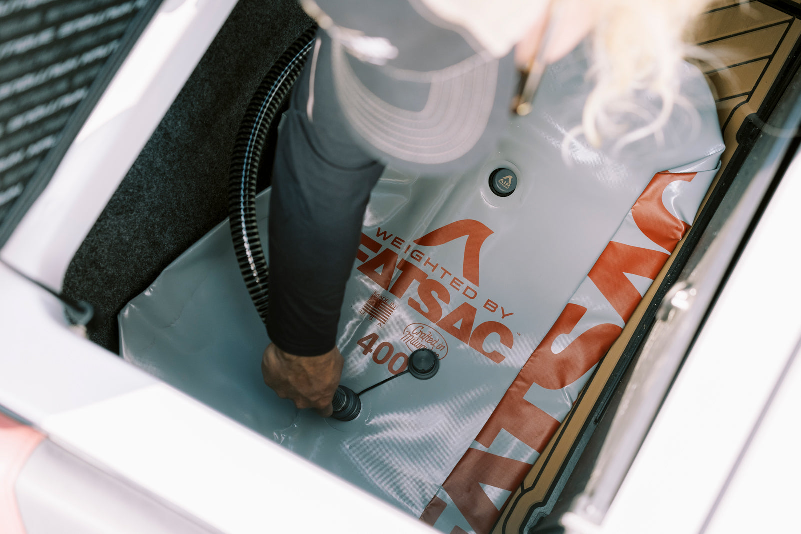Person securing a valve on a FatSac ballast bag in a boat.