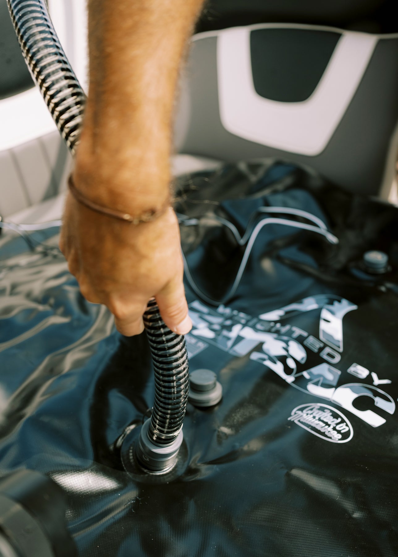 Person attaching a hose to a black inflatable bag with printed text.