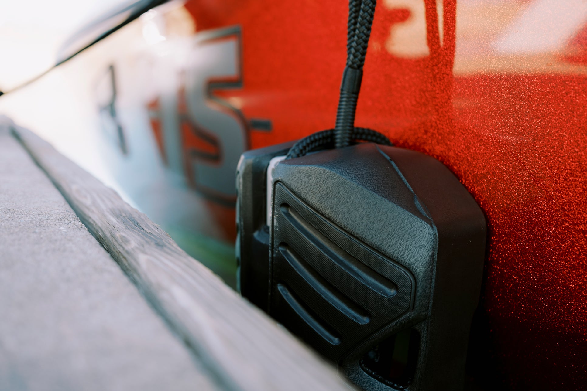 Close-up of a black boat fender attached to a shiny red boat.