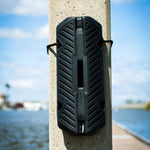 Fatsac black fender with dock line attached to a concrete pillar by the waterfront.