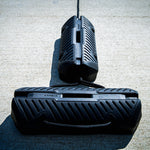 Fatsac black boat fender with straps on a concrete dock.