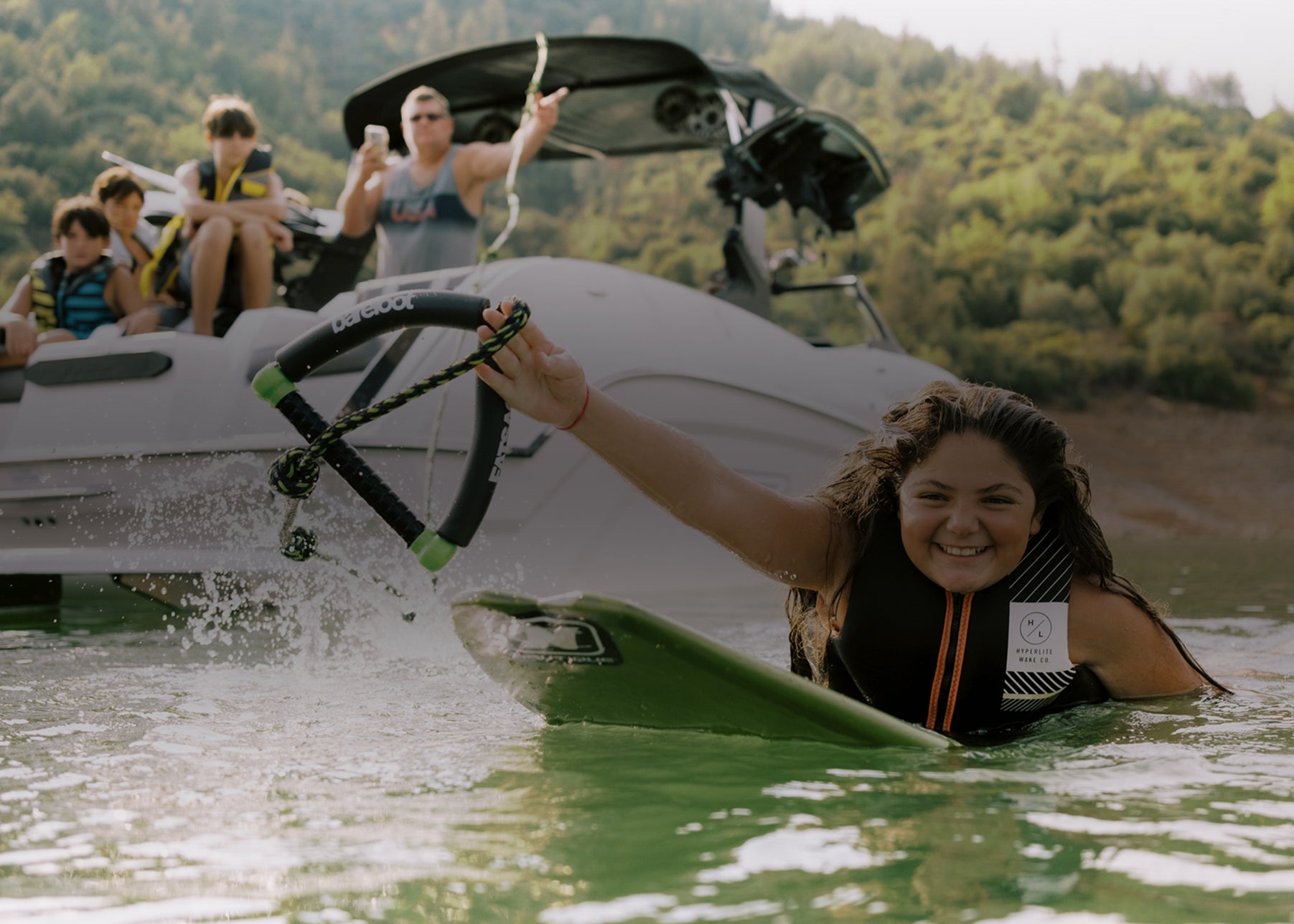 Person waterskiing near a boat with people cheering in the background.