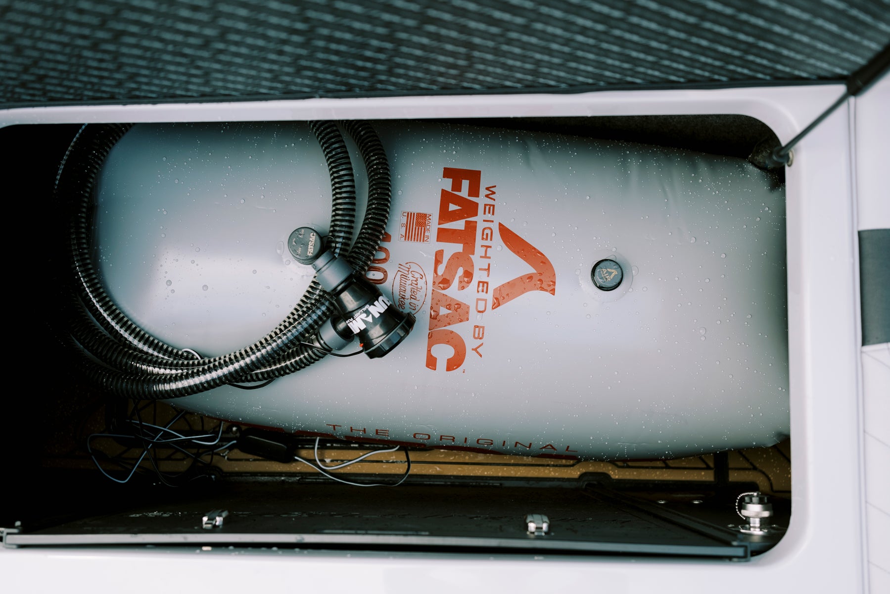 Fatsac ballast bag with hoses in a boat storage compartment.