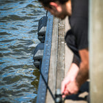 Person on a dock, dock line taut as they face the water.