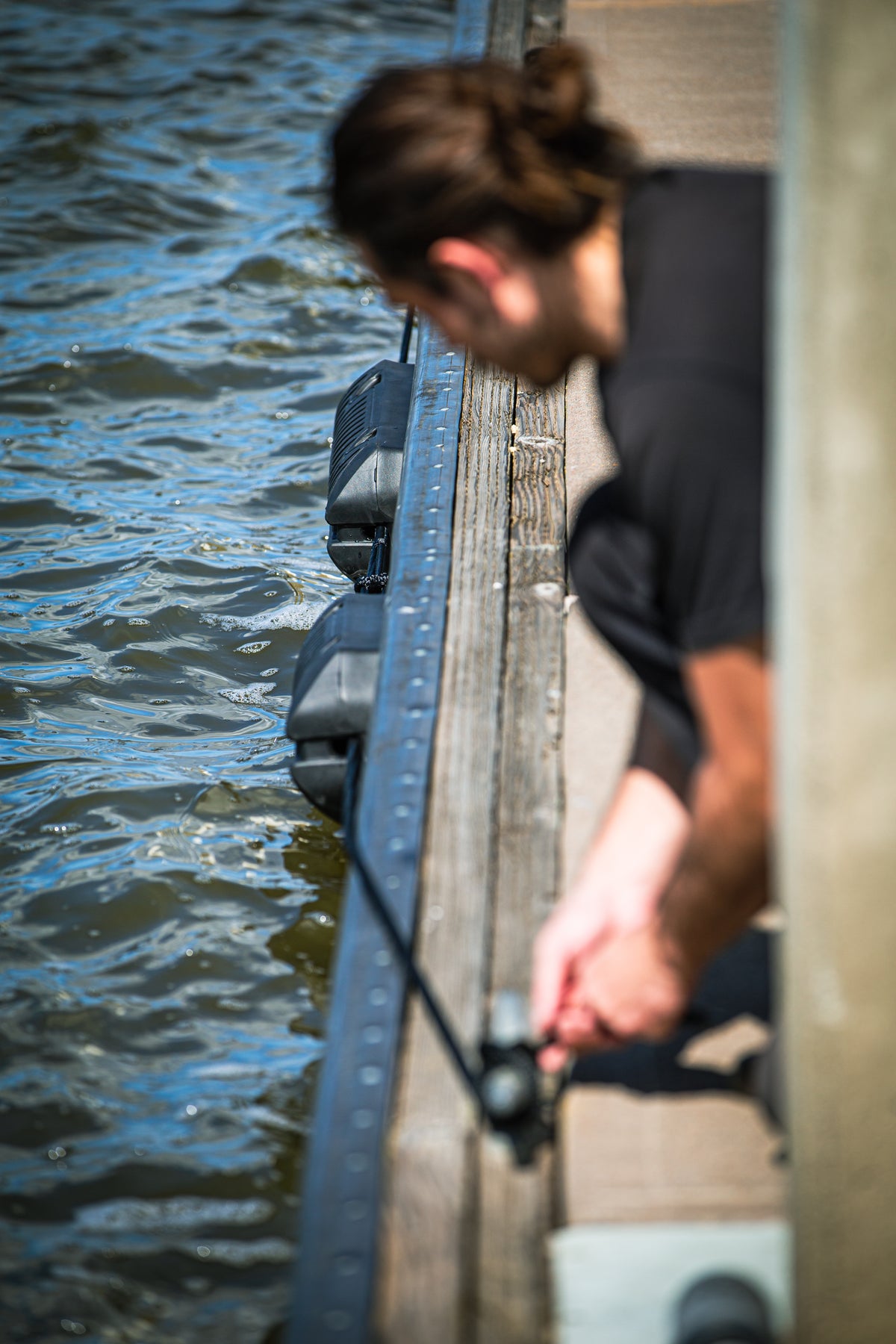 Person on a dock, dock line taut as they face the water.