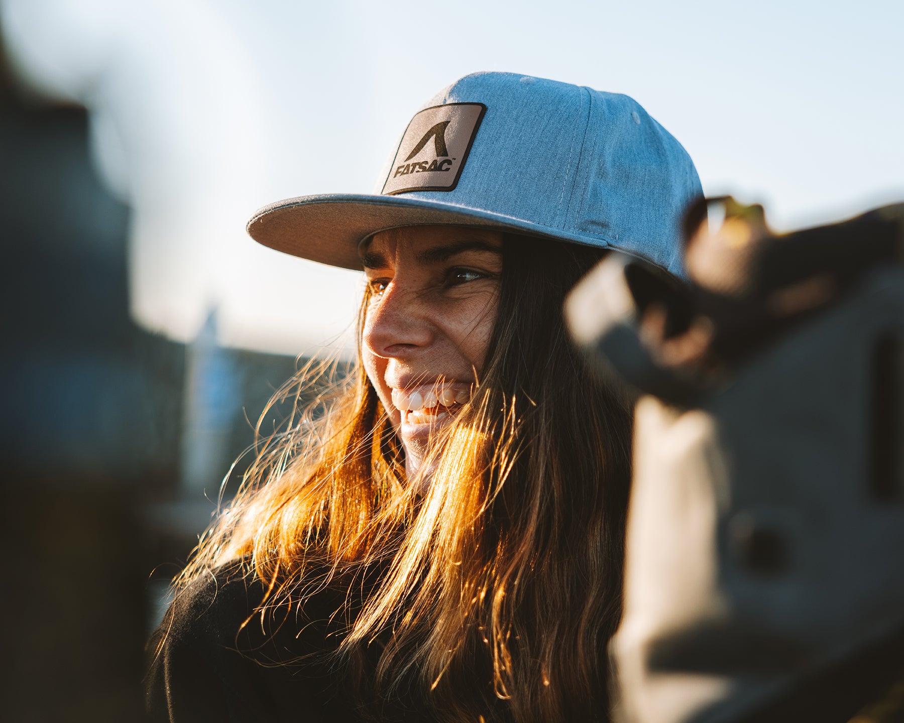Woman in a gray cap smiling in sunlight.