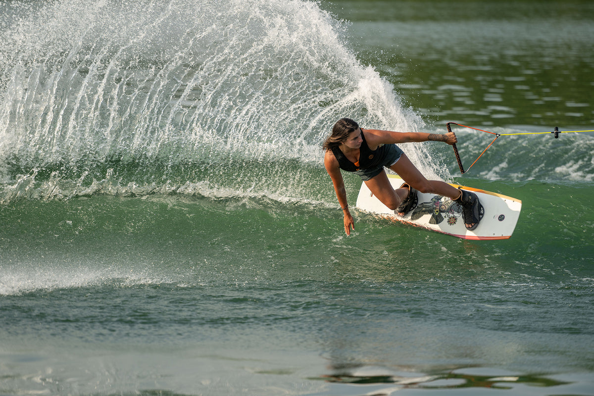 A person wakeboarding skillfully, creating a splash with a sharp turn on the water.