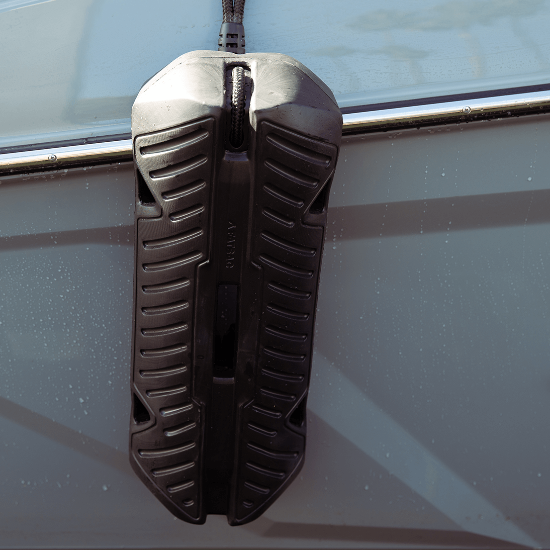 Fatsac boat fender with bungee cable hanging on a vessels side.